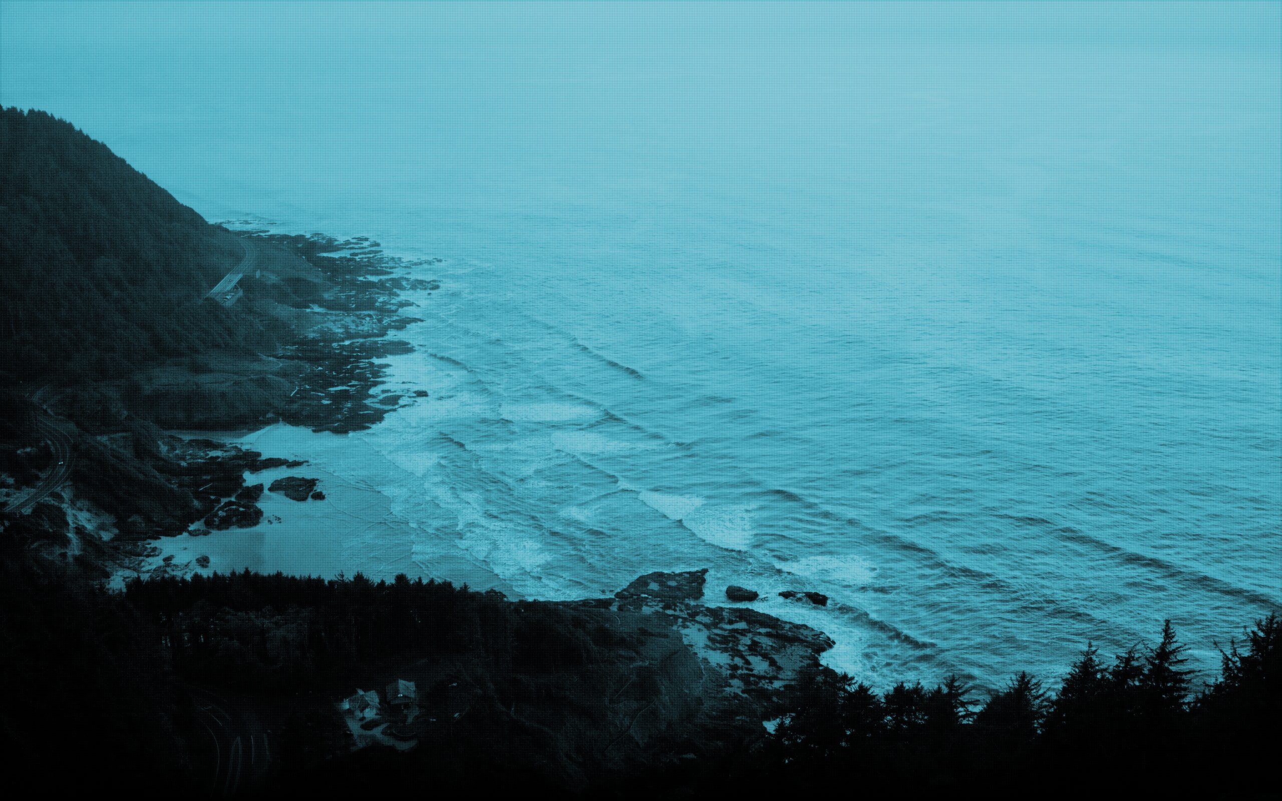 A forested headland dropping into cold, open water at dusk